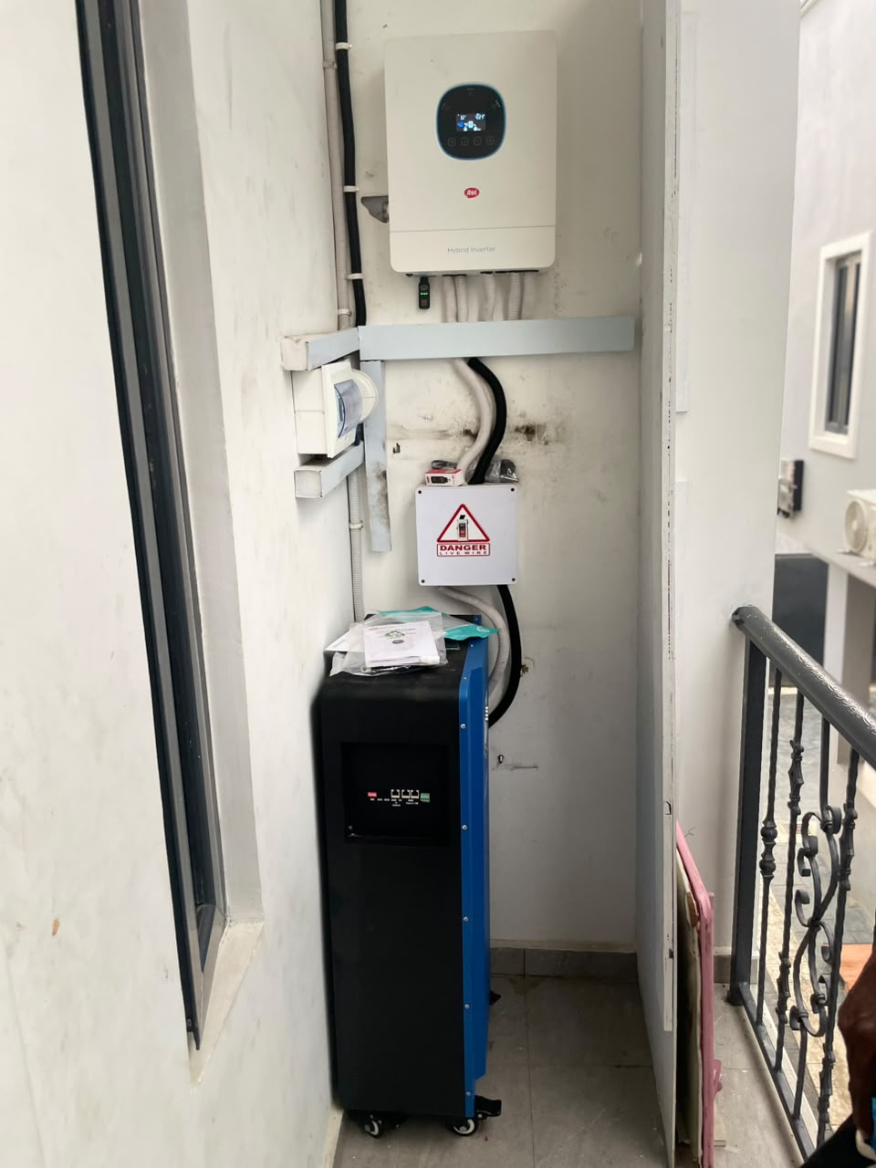 Hybrid inverter installed on a wall beside a mobile battery unit